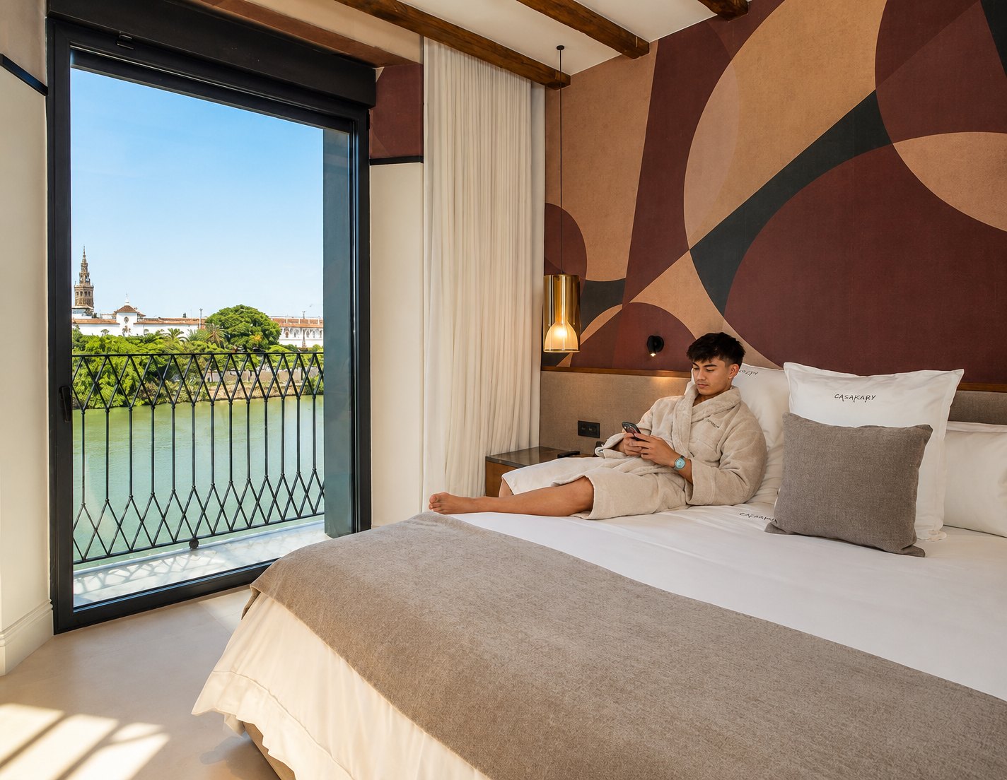 Suite de CasaKary con mural geométrico y la Giralda al fondo del ventanal