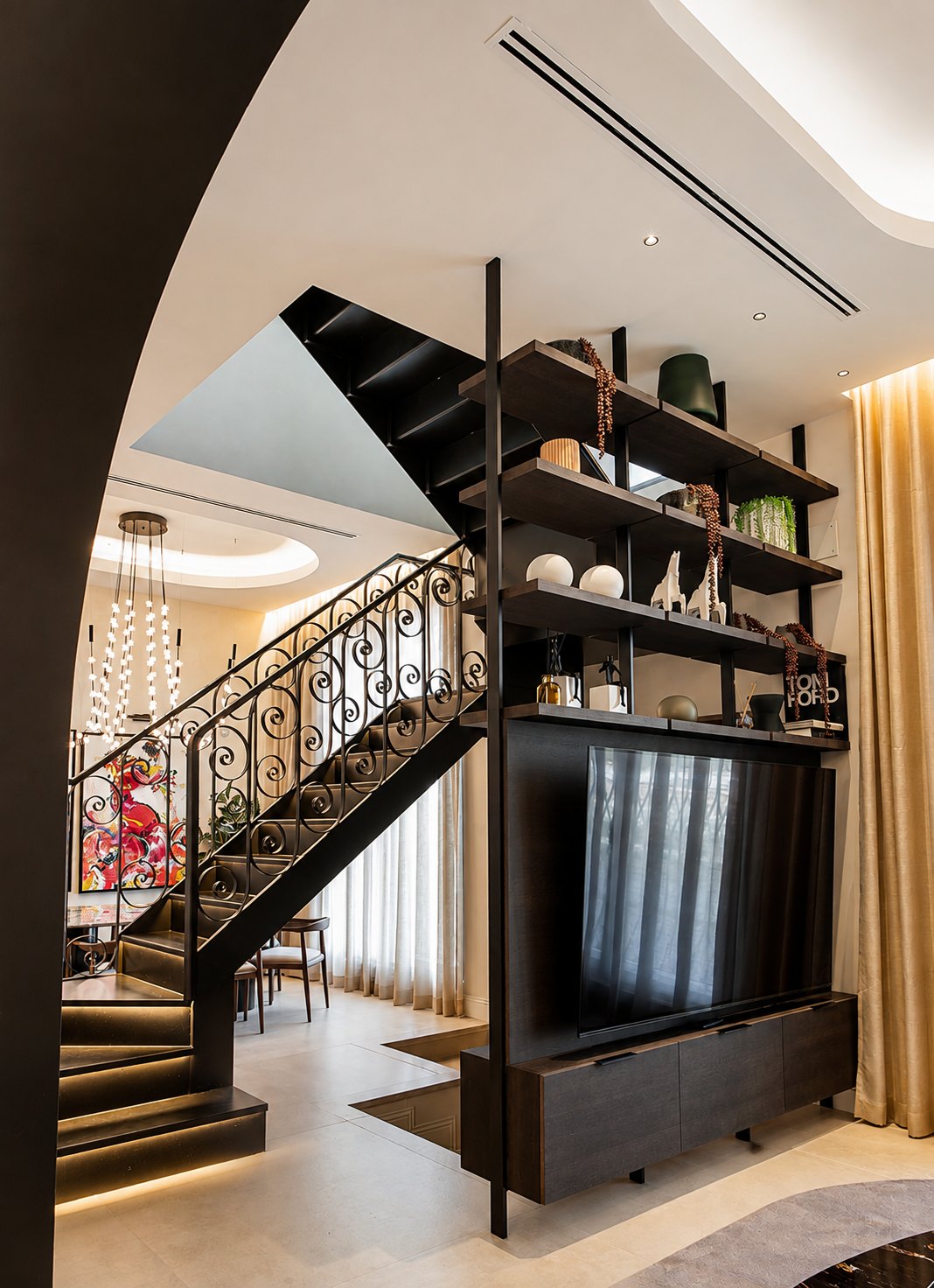 Salón de CasaKary con escalera de forja y lámpara de cristal